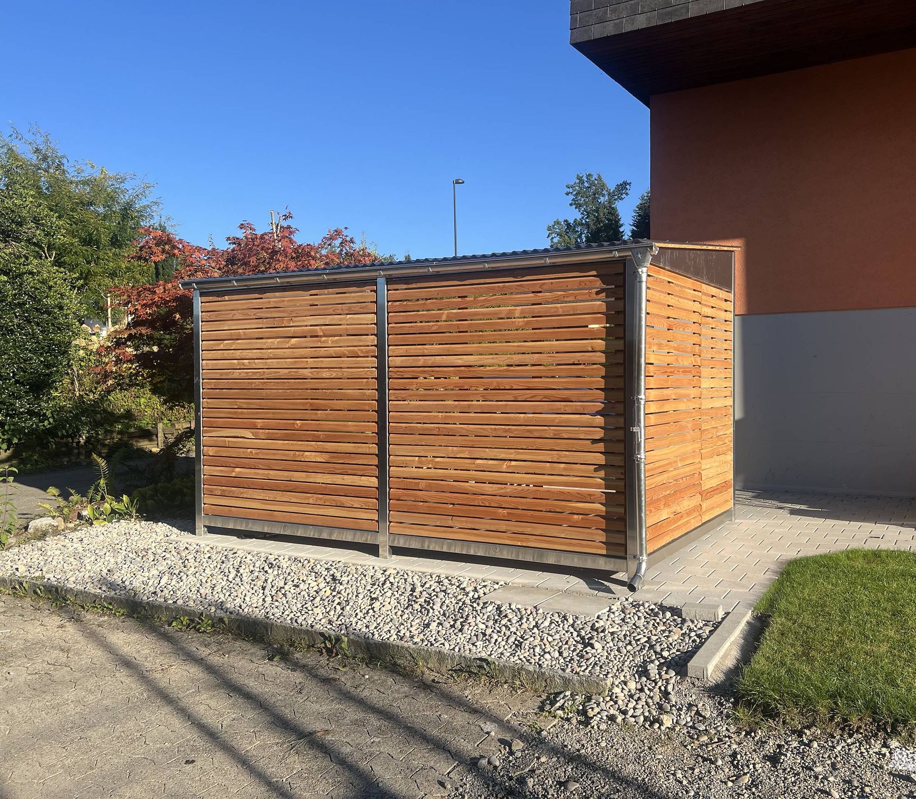 Geschlossene Längsseite mit Holzlattung, von der Strasse aus