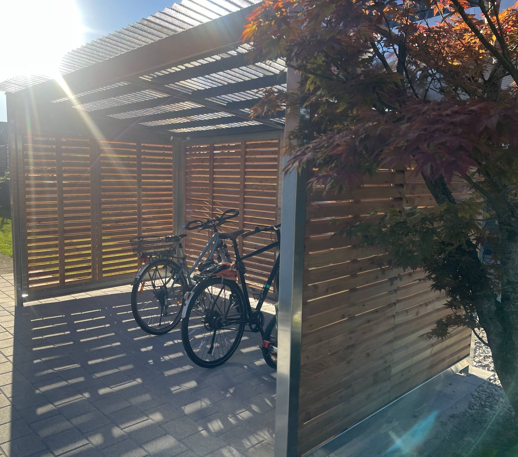 Zwei Velos im Unterstand, Sonnenlicht fällt durch das Dach